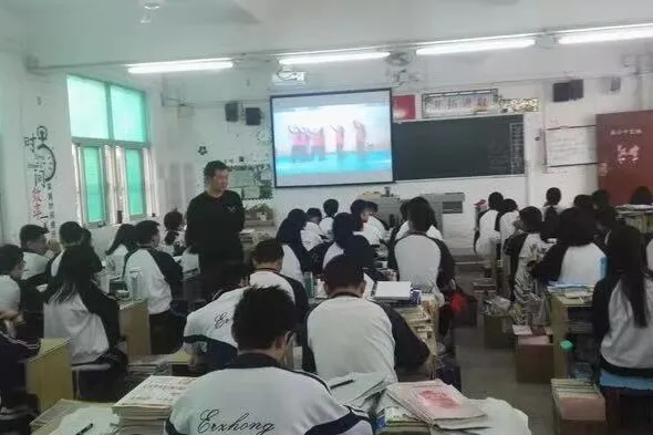A classroom in session, students at their desks with the lesson on screen